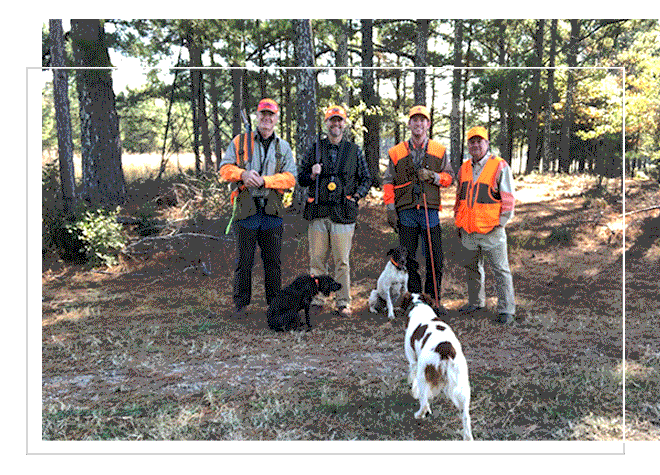 McGarity Group lawyers in the woods in hunting clothes with dogs